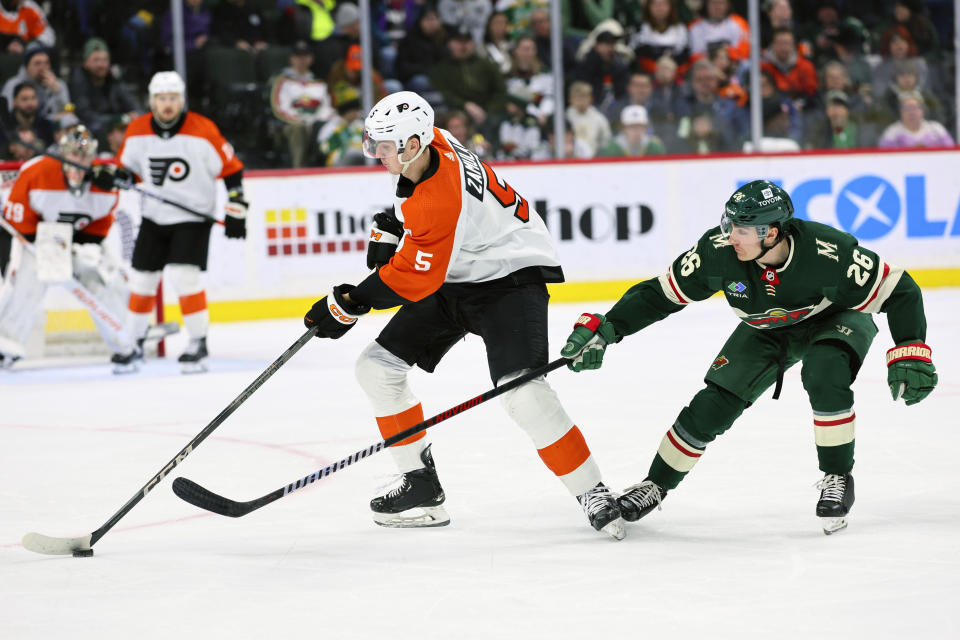 Philadelphia Flyers defenseman Egor Zamula (5) and Minnesota Wild center Connor Dewar (26) fight for the puck during the second period of an NHL hockey game Friday, Jan. 12, 2024, in St. Paul, Minn. (AP Photo/Adam Bettcher)