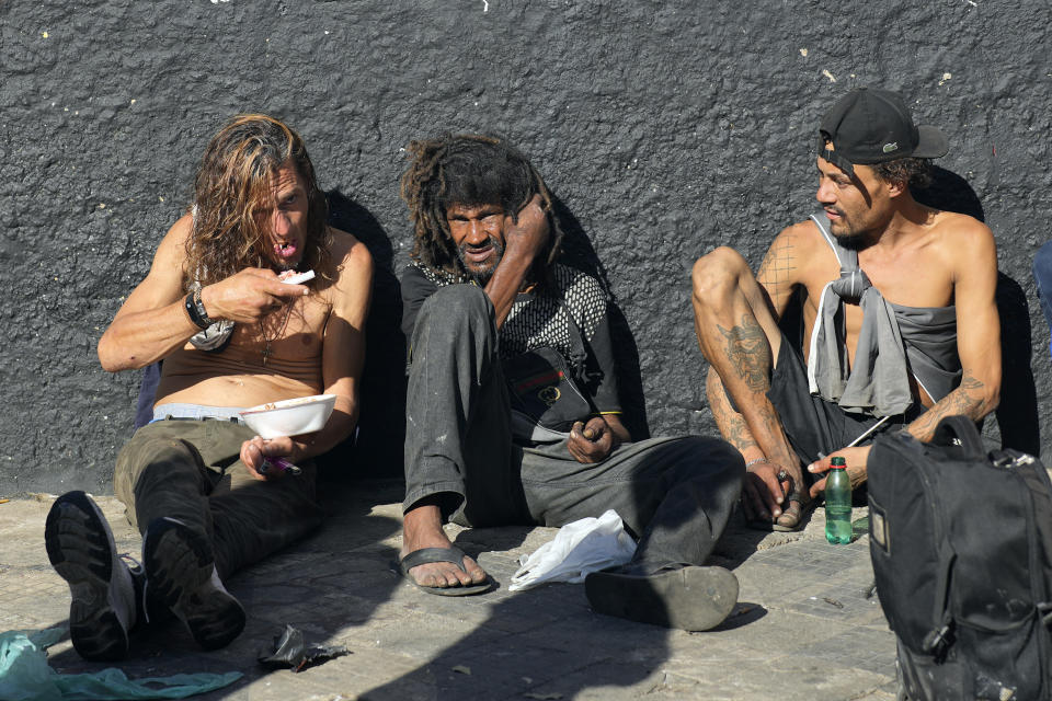 FILE - Crack users watch a performance by Flavio Falcone, known as the clown doctor of Crackland, in downtown Sao Paulo, Brazil, May 11, 2023. The decline of Sao Paulo's downtown area has accelerated over the last year, where crack users seem to be everywhere, roaming the central streets of South America's biggest city. (AP Photo/Andre Penner, File)