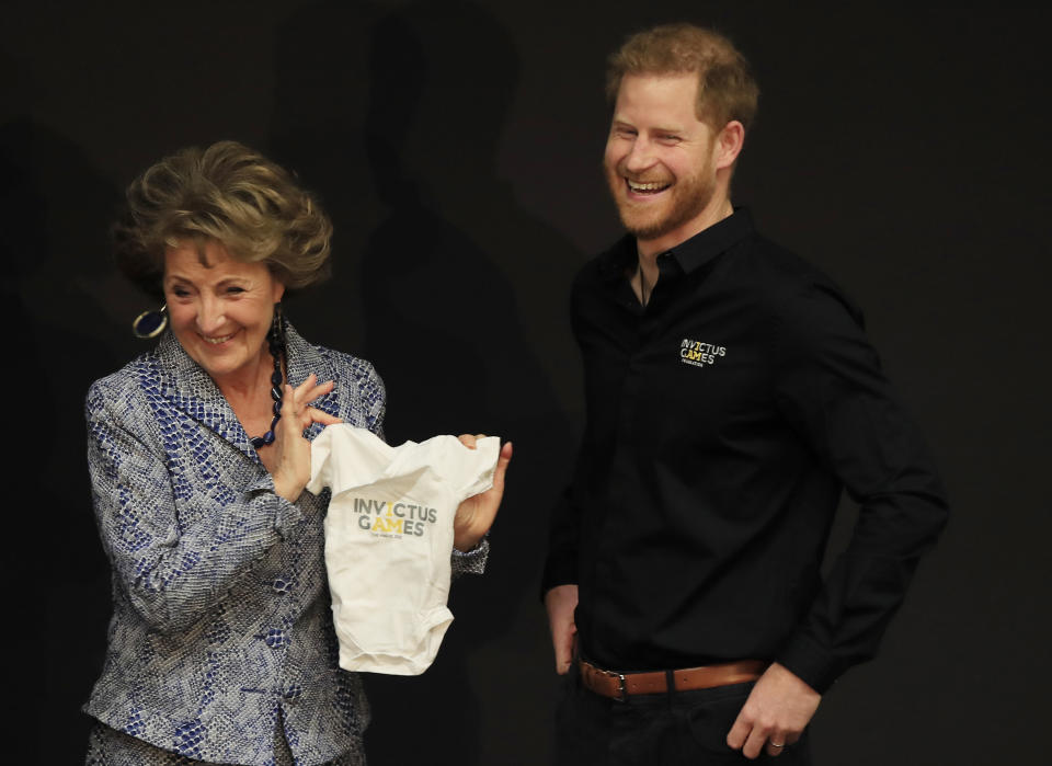 Princess Margriet of the Netherlands presents Britain's Prince Harry with an outfit for his newborn son at the launch of the 2020 Invictus Games, in The Hague, Netherlands, Thursday, May 9, 2019. Prince Harry returned to his royal duties Thursday after the birth of his son Archie Harrison, to launch the countdown for the fifth Invictus Games sports competition for injured service personnel and veterans. (AP Photo/Peter Dejong)