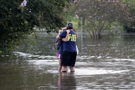 Renton Affray, a firefighter with the St. Amant Fire Department, embraces his girlfriend Malie Geautrux on a flooded street in St. Amant, Louisiana, U.S., August 15, 2016. REUTERS/Jonathan Bachman