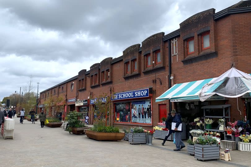 A street with a flower shop and pedestrians