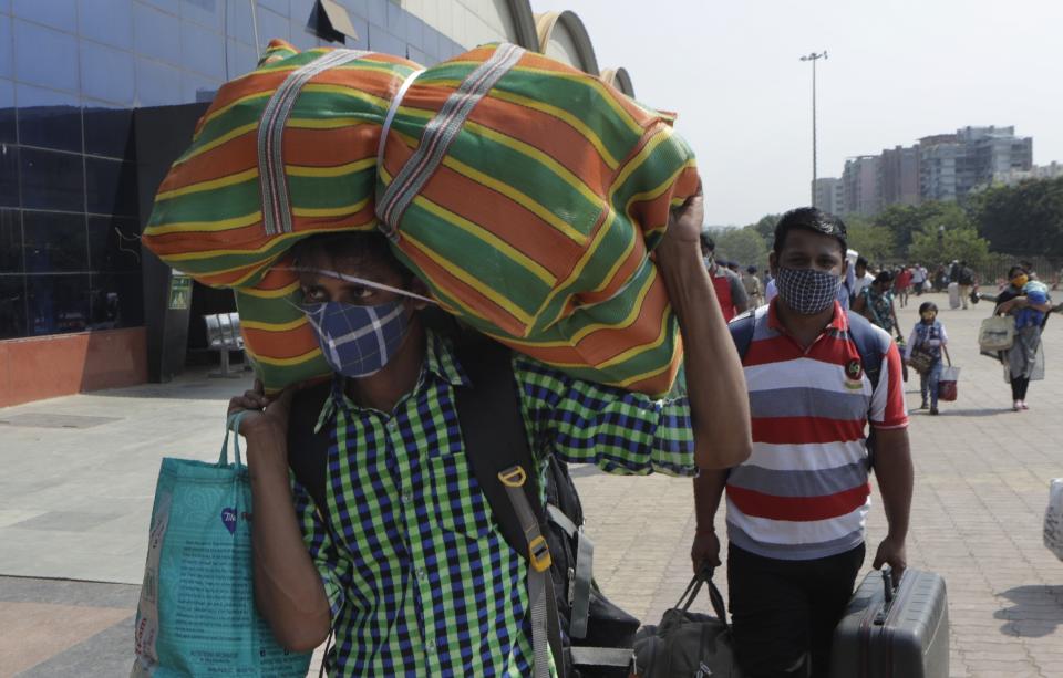 People wearing masks as a precaution against the coronavirus walk to board trains at Lokmanya Tilak Terminus in Mumbai, India, Friday, April 16, 2021. Migrant workers are swarming rail stations in India's financial capital Mumbai to go to their home villages as virus-control measures dry up work in the hard-hit region. The government of Maharashtra state imposed lockdown-like curbs on Wednesday for 15 days to check the spread of the virus. It closed most industries, businesses and public places and limited the movement of people, but didn’t stop the bus, train and air services. An exodus ensued, with panicked day laborers hauling backpacks onto overcrowded trains leaving Mumbai, travel that raises fears of infections spreading in rural areas. (AP Photo/Rajanish Kakade)