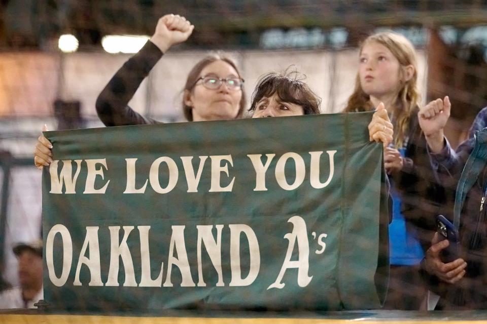 A fan holds a sign that reads we love you Oakland A's during the ninth inning of a game between the Oakland Athletics and the Texas Rangers at Oakland-Alameda County Coliseum.