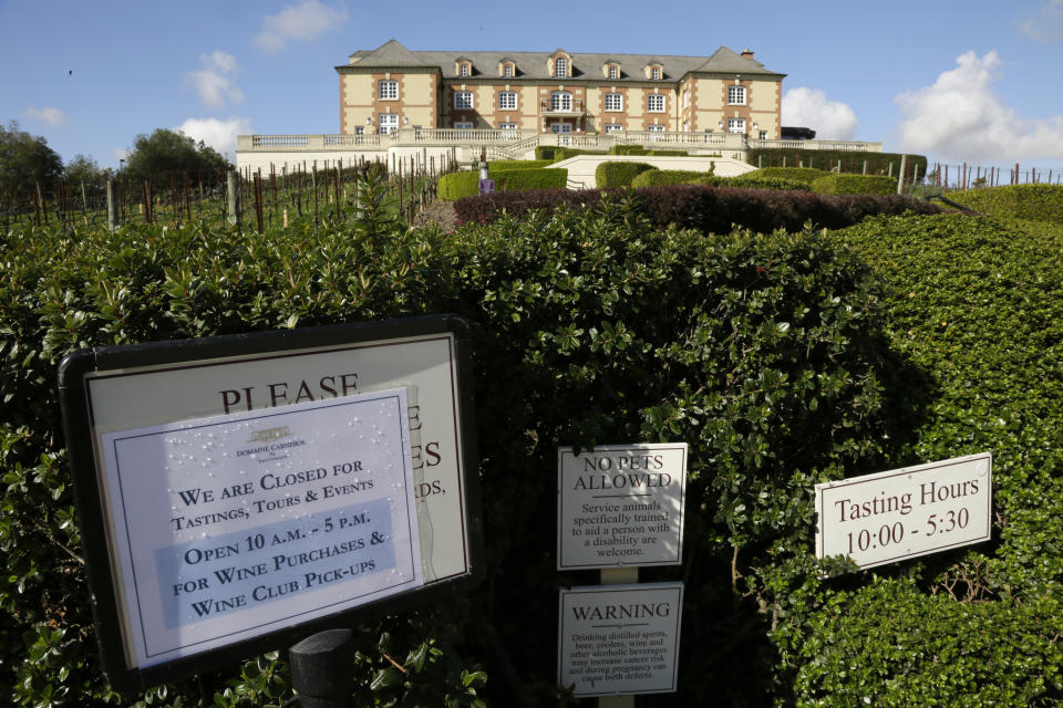 A sign outside the Domaine Carneros winery tells people they are closed for tastings and tours, but open for purchases and wine club pickups Thursday, March 19, 2020, in Napa, Calif. As worries about the spread of the coronavirus confine millions of Californians to their homes, concern is growing about those who have no homes in which to shelter. (AP Photo/Eric Risberg)