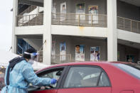 FILE - Posters of former Pawtucket Red Sox minor league baseball players decorate McCoy Stadium as a motorist is swabbed for COVID-19 at a testing site in Pawtucket, R.I, in this Wednesday, Dec. 9, 2020, file photo. Following a year without a season due to the coronavirus pandemic, thousands of minor league players are finally returning to work. (AP Photo/David Goldman, File)