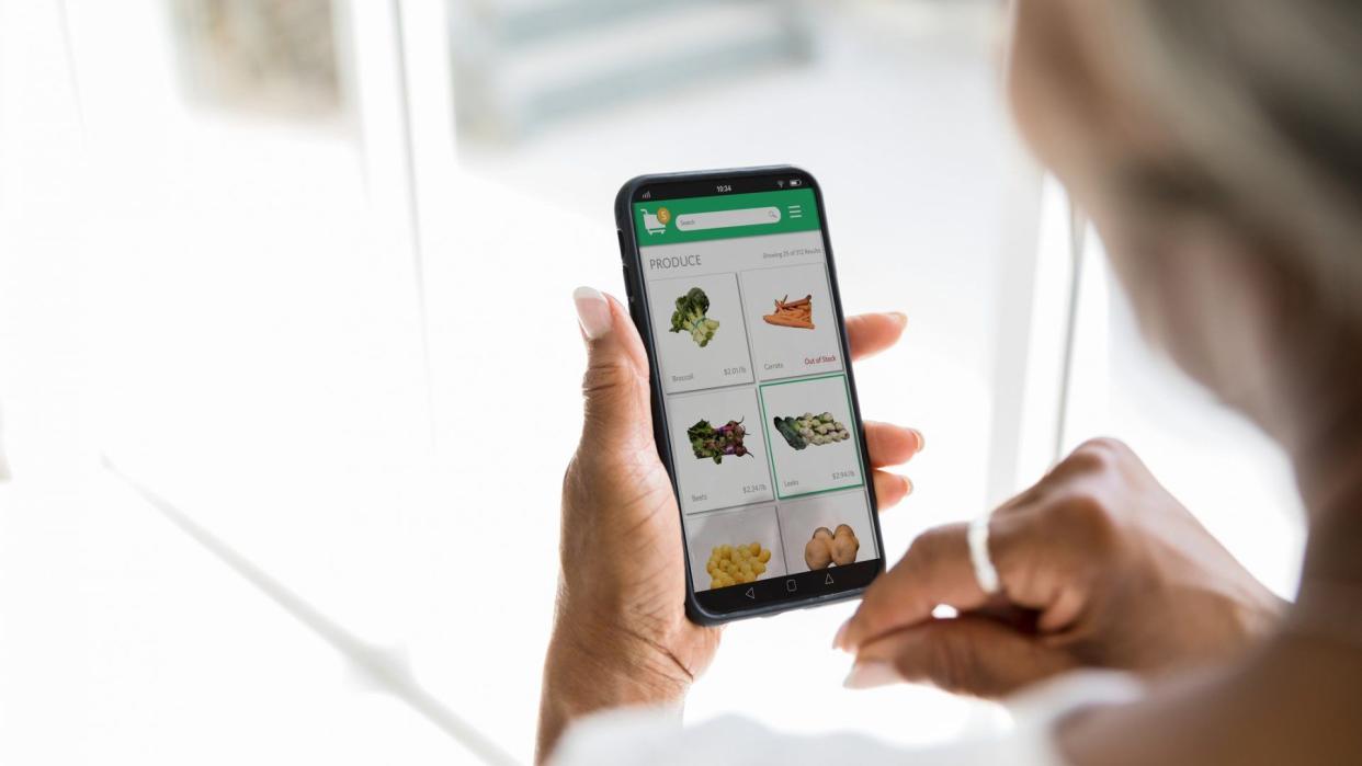 A woman uses a grocery delivery app on her smartphone.