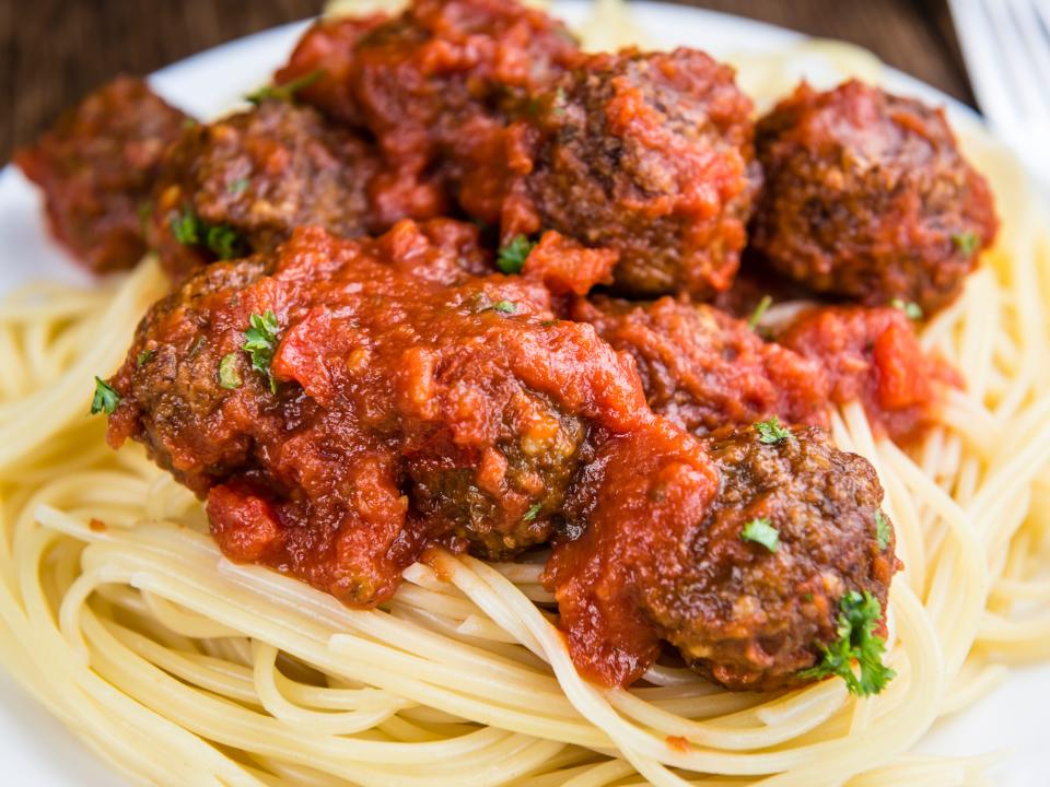 Spaghetti and large meatballs on a white plate.