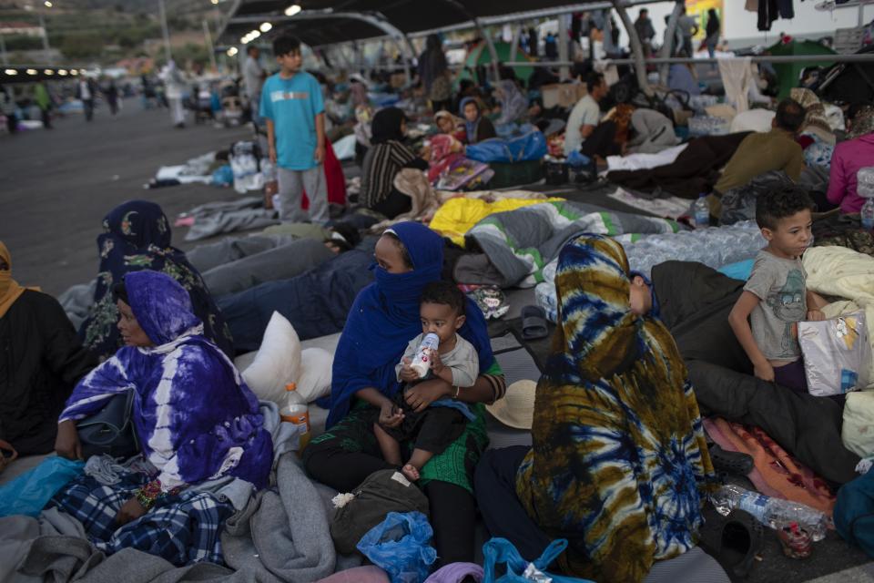 Migrants gather at the parking area of a supermarket on the northeastern island of Lesbos, Greece, Friday, Sept. 11, 2020. The Greek government says thousands of migrants left homeless after fires gutted a sprawling refugee camp on the island of Lesbos will not be allowed to travel to mainland Greece. (AP Photo/Petros Giannakouris)