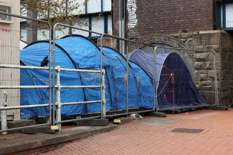 Two blue tents behind a section of fence