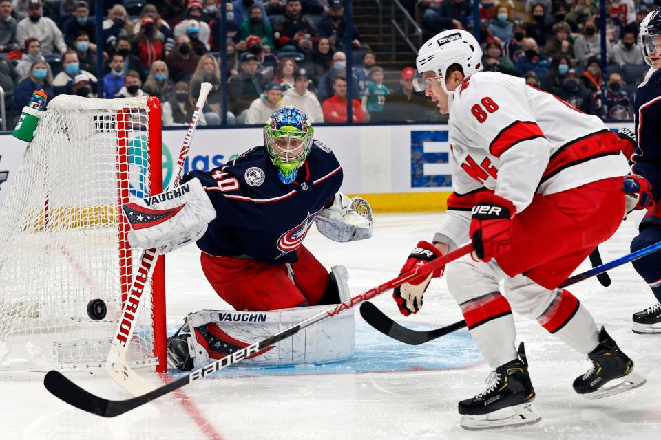 Columbus Blue Jackets' Daniil Tarasov, left, makes a save against Carolina Hurricanes' Martin Necas during the first period of an NHL hockey game Saturday, Jan. 1, 2022, in Columbus, Ohio. (AP Photo/Jay LaPrete)