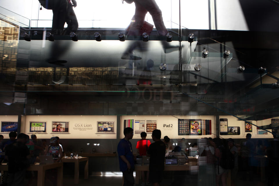 Visitors look at computer products near advertisement for Apple's iPad tablet computer at an Apple store in Beijing, China, Monday, July 2, 2012. Apple agreed to pay $60 million to settle a dispute in China over ownership of the iPad name, a court announced Monday, removing a potential obstacle to sales of the popular tablet computer in the key Chinese market. (AP Photo/Ng Han Guan)