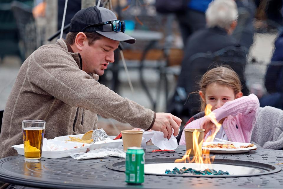 Eden Maracco, 8, has lunch her dad Jeffery while power is out at her home, at Reds Food Truck Corner in Southern Pines, N.C., Monday, Dec. 5, 2022. Tens of thousands of people braced for days without electricity in a North Carolina county where authorities say two power substations were shot up by one or more people with apparent criminal intent. (AP Photo/Karl B DeBlaker)