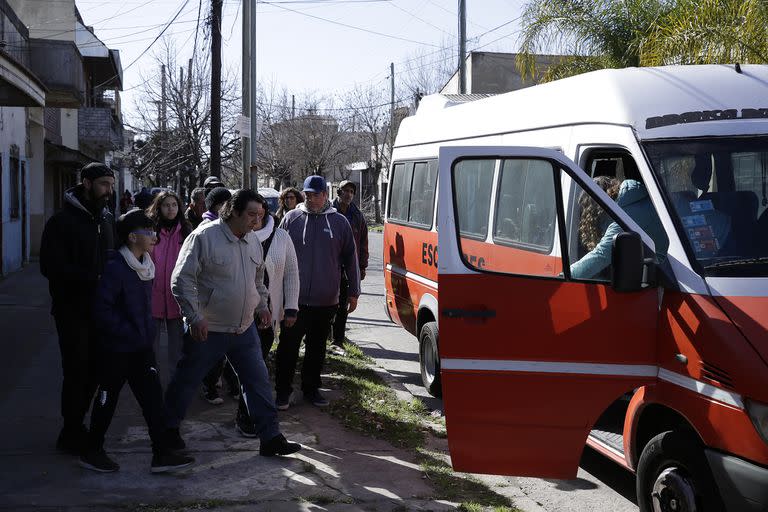 La gente sube a uno de los transportes escolares que los llevan a otra escuela