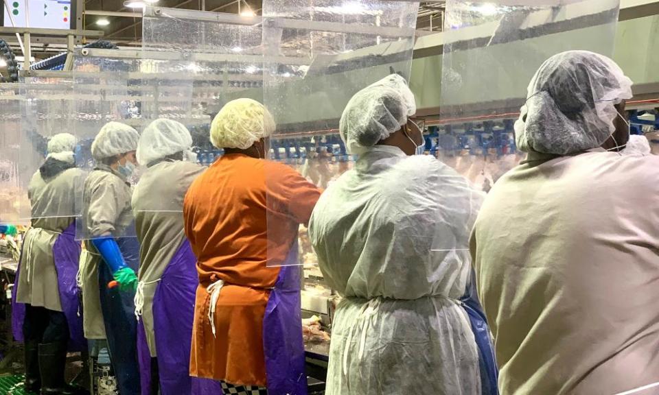 In this April 2020 photo provided by Tyson Foods, workers wear protective masks and stand between plastic dividers at the company’s Camilla, Georgia, poultry processing plant.