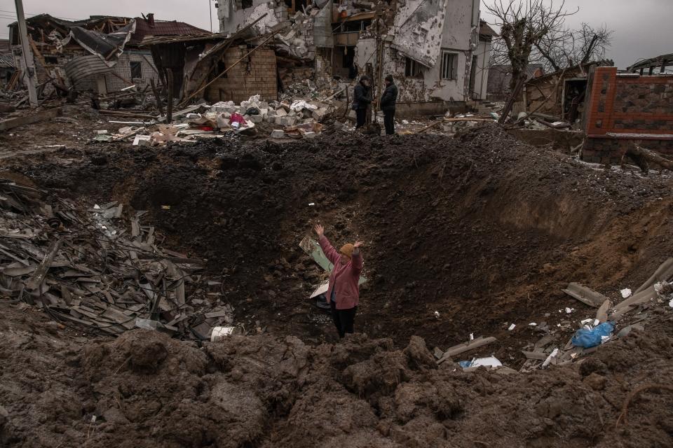 A woman waves as she stands in a crater following the Russian missile attacks on 26 January 2023 in an urban-type settlement Hlevakha, outside Kyiv, Ukraine (Getty Images)