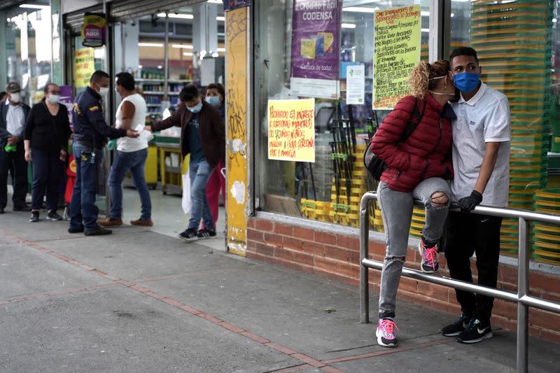 Personas usando tapabocas hacen fila, antes del comienzo del aislamiento obligatorio de 19 días decretado por el Gobierno como medida preventiva contra la propagación del coronavirus, en en las afueras de un supermercado para comprar alimentos en Bogotá