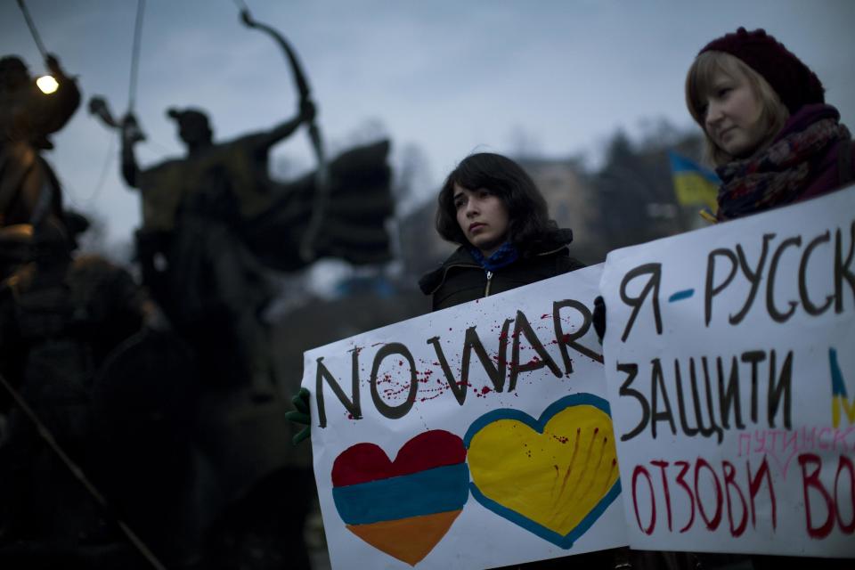 Ukrainian Maria, 23, right, and Vanui, 22, hold posters against Russia's military intervention in Crimea, in Kiev, Ukraine, Sunday, March 2, 2014. Russia's parliament approved a motion to use the country's military in Ukraine after a request from President Vladimir Putin as protests in Russian-speaking cities turned violent Saturday, sparking fears of a wide-scale invasion. The poster in the right side reads in Ukrainian: "I am from Russia, please protect me and remove the weapons and soldiers from Ukraine." (AP Photo/Emilio Morenatti)