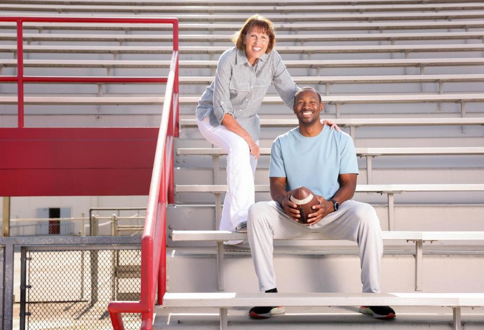 Friends Jeannine Ball, 69, left, and Antoine Cason, 38, sit in the bleachers of Lakewood High School's football stadium.