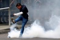 Demonstrator kicks a tear gas canister during a protest against the increase in the subway ticket prices in Santiago