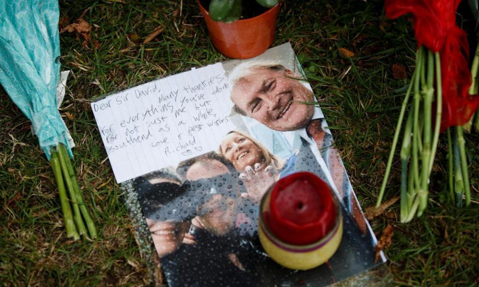 Floral tributes and a handwritten message attached to a picture of David Amess