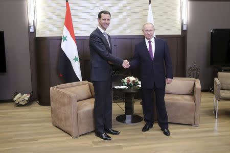 Russian President Vladimir Putin (R) shakes hands with Syrian President Bashar al-Assad during a meeting in the Black Sea resort of Sochi, Russia November 20, 2017. Sputnik/Mikhail Klimentyev/Kremlin via REUTERS