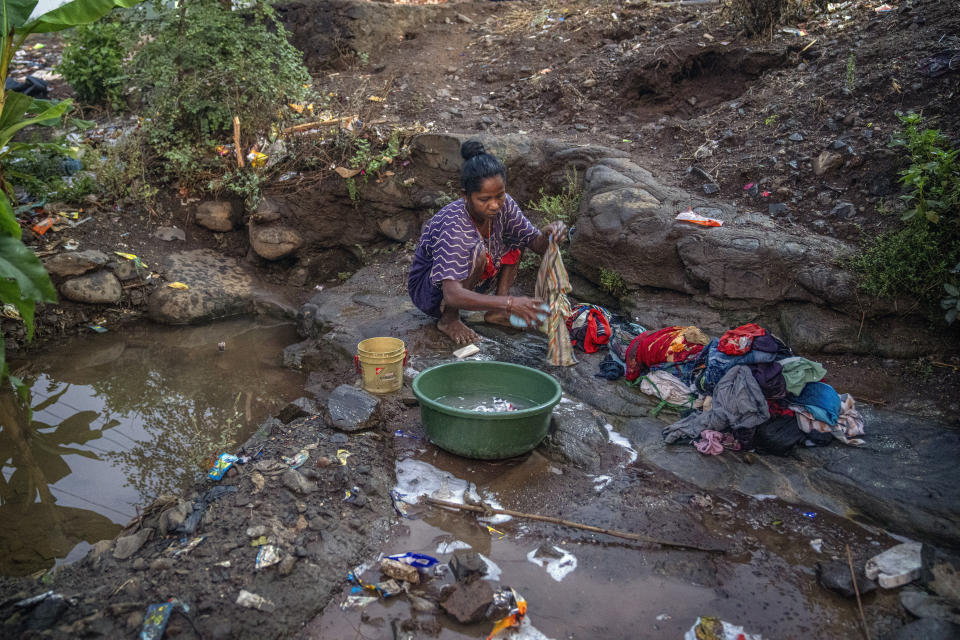 Rekha Wagh washes clothes early in the morning by a sewer near Shahapur, northeast of Mumbai, India, Saturday, May 6, 2023. She said, "I have been getting up before sunrise to wash clothes since my childhood. Even here, there are a lot of quarrels later in the day to find a spot." (AP Photo/Dar Yasin)