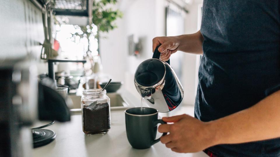 A coffee mug being filled with coffee from a French press on a countertop