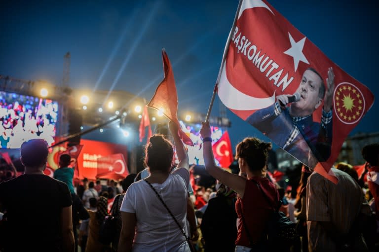 A pro-Erdogan supporter holds a portrait flag of Turkish President Recep Tayyip Erdogan reading "Commander in Chief" during a rally against the military coup on Taksim square in Istanbul on July 25, 2016