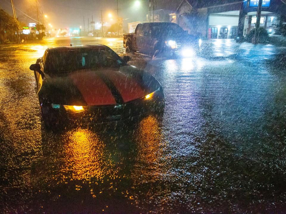 Motorists navigate a flooded Gause Boulevard in Slidell, Louisiana late on Friday 18 June 2021 (AP)