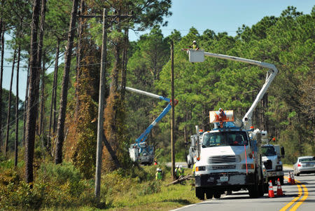 Utility workers repair power lines on U.S. Highway 98 near Alligator Point in the aftermath of Hurricane Michael in Franklin County, Florida, U.S., October 13, 2018. REUTERS/Steve Nesius