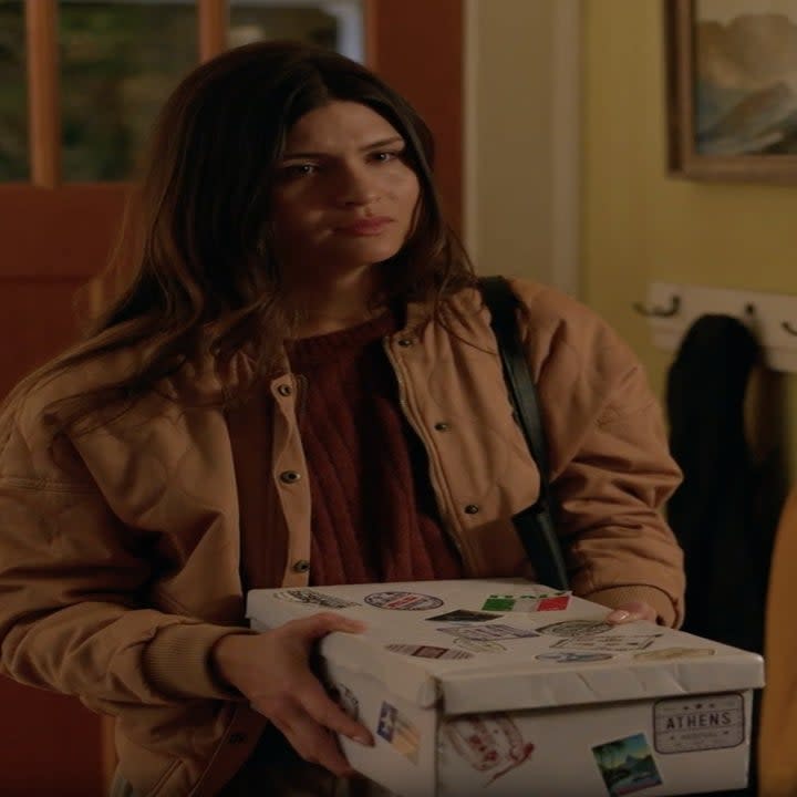 A woman stands in a hallway with a box.