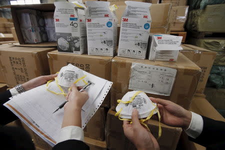 Officers show fake masks after being seized by customs in Shanghai, China, December 8, 2015. REUTERS/Stringer