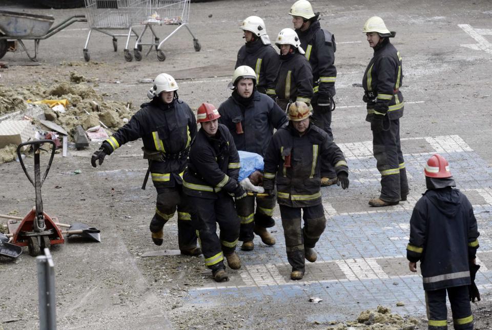 Firefighters carry a body as they remove it from a collapsed supermarket in Riga