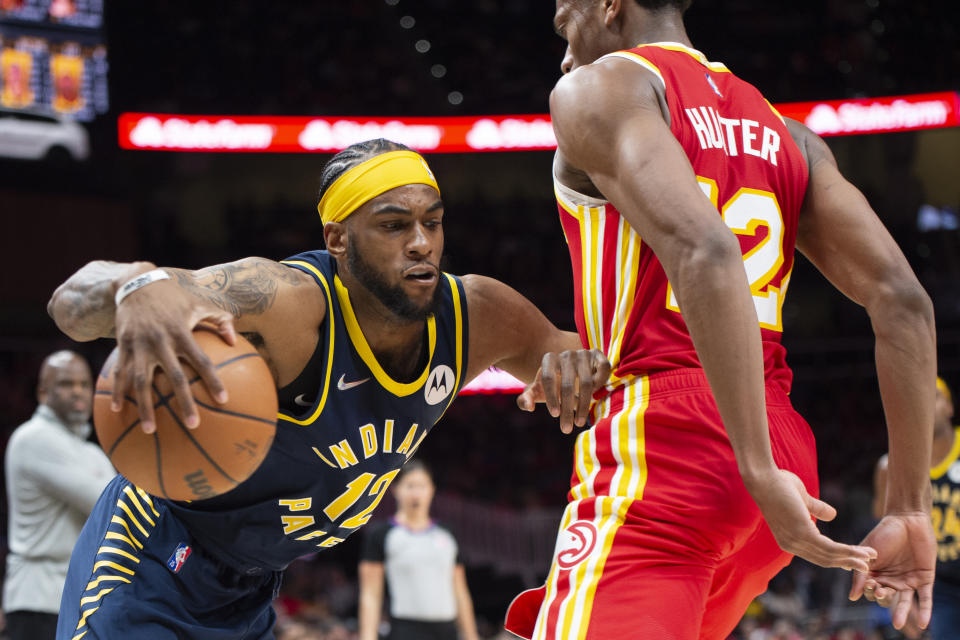 Indiana Pacers forward Oshae Brissett, left, drives past Atlanta Hawks forward De'Andre Hunter, right, during the second half of an NBA basketball game Sunday, March 13, 2022, in Atlanta. (AP Photo/Hakim Wright Sr.)