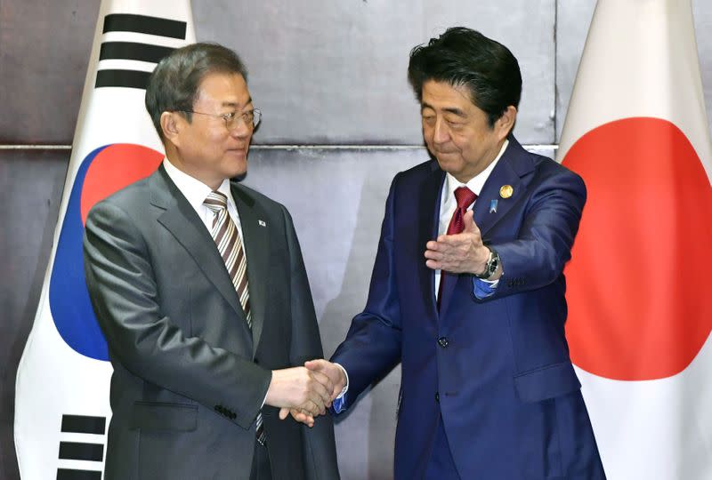 Japan's Prime Minister Shinzo Abe shakes hands with South Korea's President Moon Jae-in during their meeting in Chengdu, China