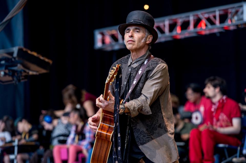 Nils Lofgren wearing a top hat and playing guitar.