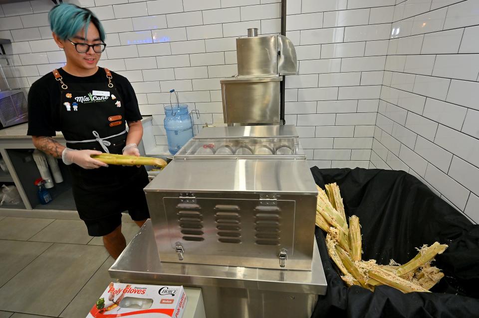 Mia Cane Juicery & Acai Bar employee Tyler Tran of Grafton presses sugar canes for the juice.