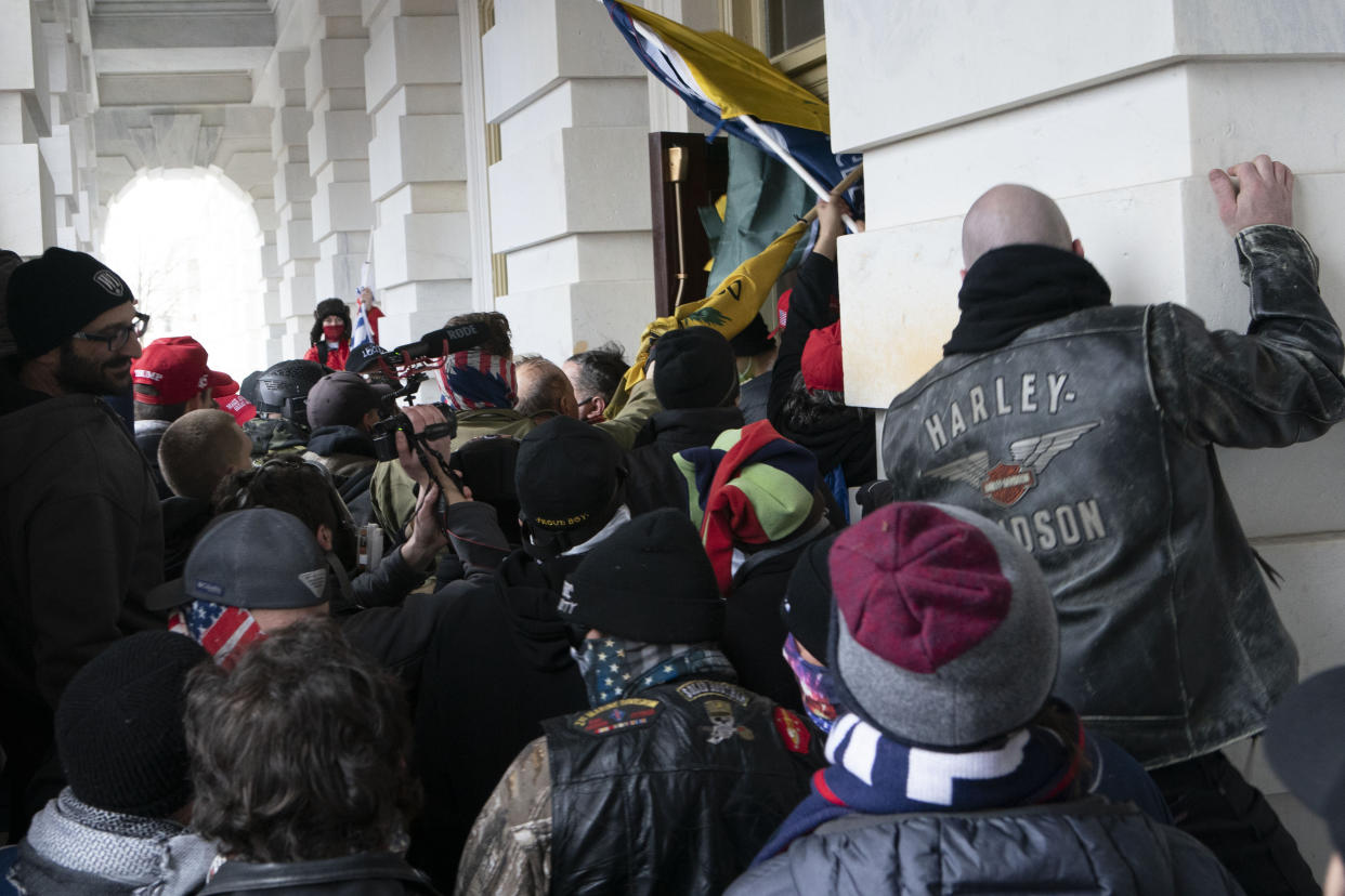 FILE - Insurrectionists loyal to President Donald Trump try to open a door of the U.S. Capitol as they riot in Washington, Jan. 6, 2021. Three active-duty Marines have been charged in the riot at the U.S. Capitol. Court records show that Micah Coomer, Joshua Abate and Dodge Dale Hellonen were arrested this week on misdemeanor charges after fellow Marines helped investigators identify them in footage among the pro-Trump mob on Jan. 6, 2021. (AP Photo/Jose Luis Magana, File)