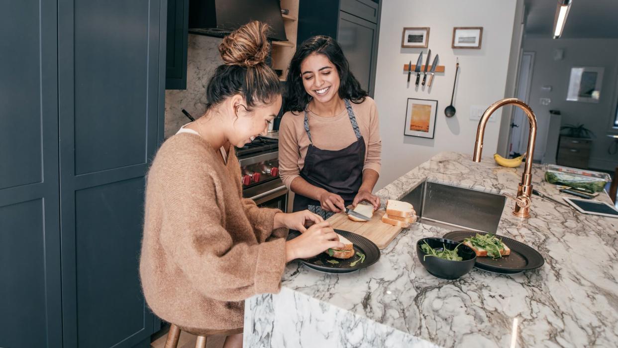 Two young students sitting on the kitchen, They are vlooging and preparing the meal.