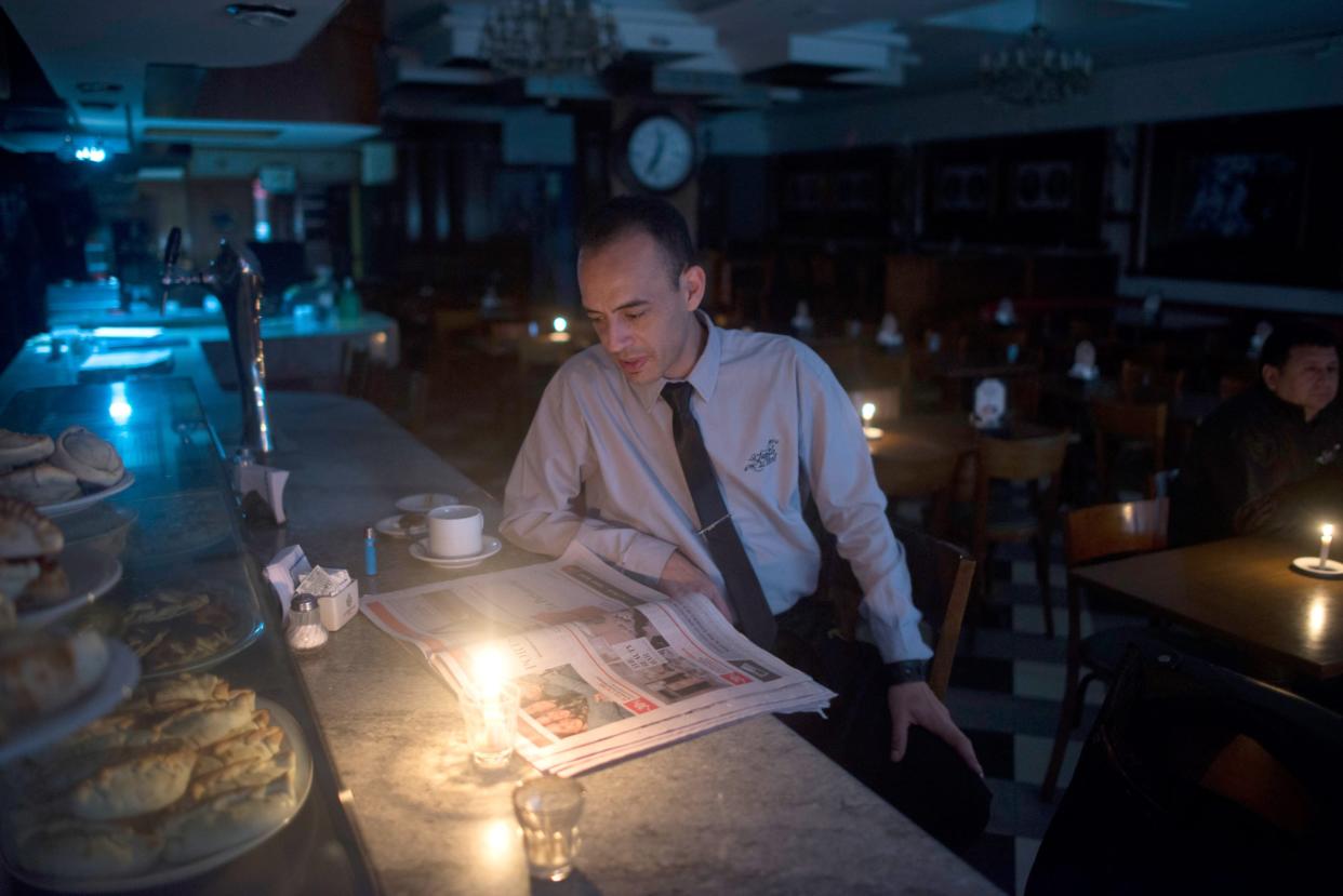 Ein Gast liest bei Kerzenlicht eine Zeitung in einer Bar in Buenos Aires, weil in Argentinien einen Tag lang der Strom ausfiel. Einen derart massiven Blackout gab es in Deutschland noch nicht. - Copyright: picture alliance/Mario De Fina