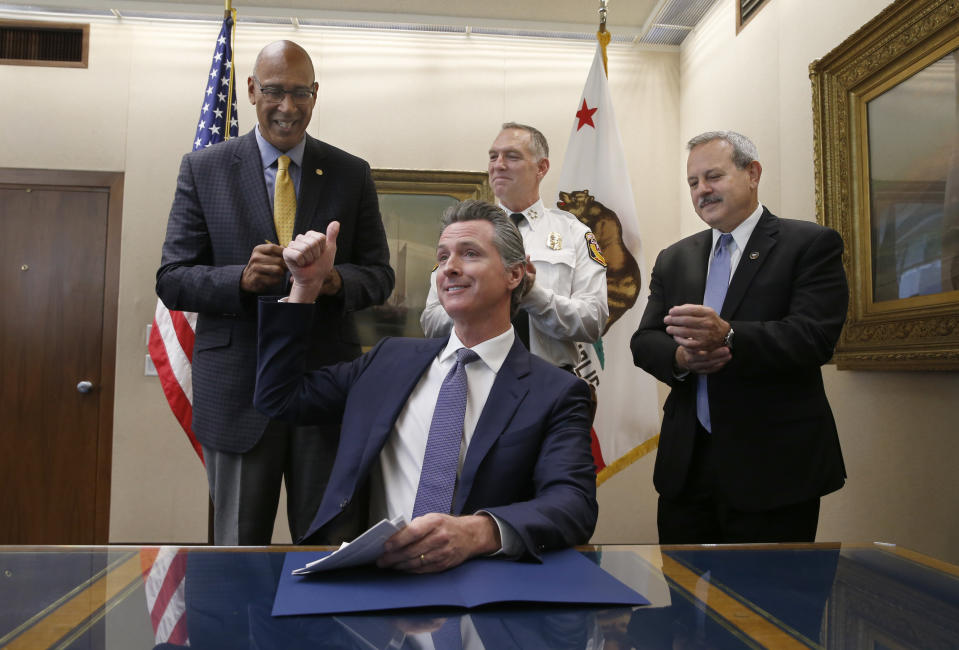 FILE - In this July 12, 2019, file photo, Gov. Gavin Newsom gives a thumbs up after signing a wildfire measure authored by Assemblyman Chris Holden, D-Pasadena, left, in Sacramento, Calif. Newsom is wrapping up a first year highlighted by the bankruptcy of the country's largest utility, an escalating homelessness crisis and an intensifying feud with the Trump administration, along with record-low unemployment and a booming state economy producing a multi-billion-dollar surplus. (AP Photo/Rich Pedroncelli, File)