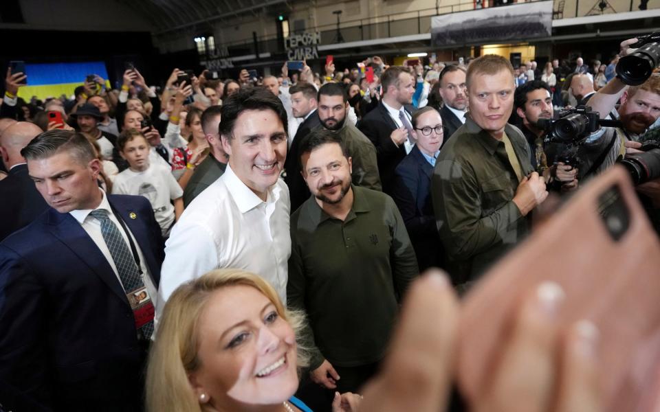 Prime Minister Justin Trudeau, center left, and Ukrainian President Volodymyr Zelenskyy, center right, pose for a selfie with a supporter after taking part in a rally at the Fort York Armoury in Toronto on Friday, Sept. 22, 2023.