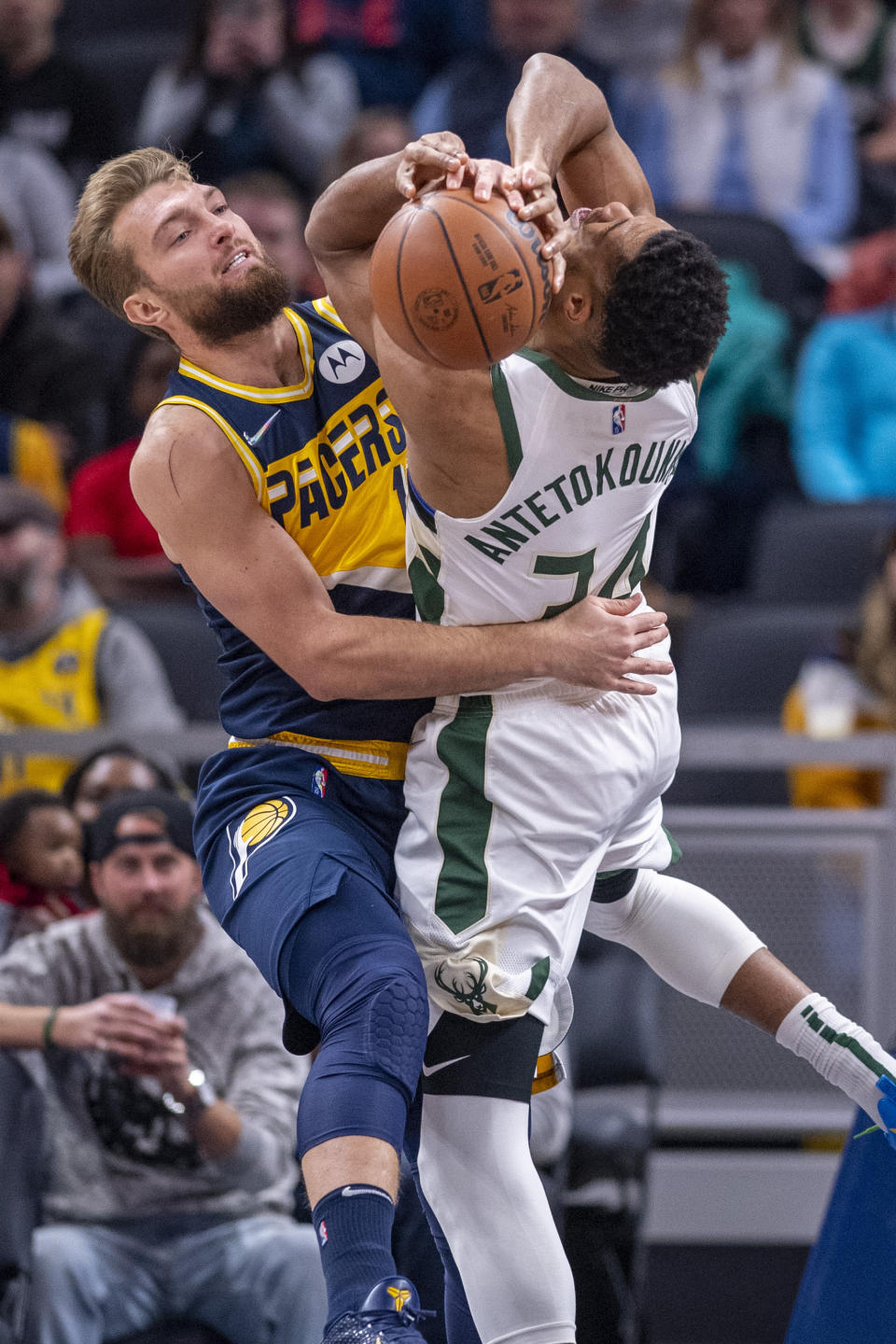 Indiana Pacers forward Domantas Sabonis, left, and Milwaukee Bucks forward Giannis Antetokounmpo (34) battle for the ball during the first half of an NBA basketball game in Indianapolis, Sunday, Nov. 28, 2021. (AP Photo/Doug McSchooler)