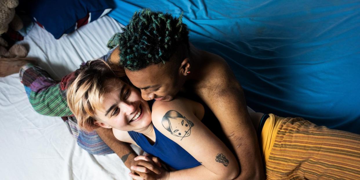 a young lgbt couple laughing and hugging in bed