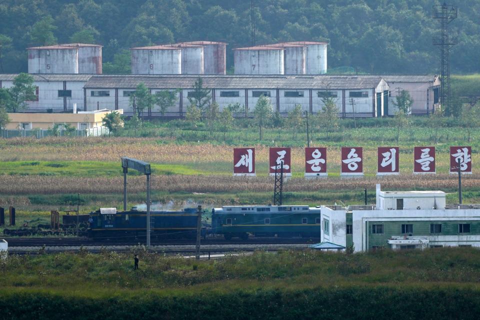 A green train with yellow trimmings, resembling one used by North Korean leader Kim Jong Un on his previous travels, is seen steaming by a slogan which reads "Toward a new victory" on the North Korea border with Russia and China seen from northeastern China's Jilin province on Sept. 11, 2023.