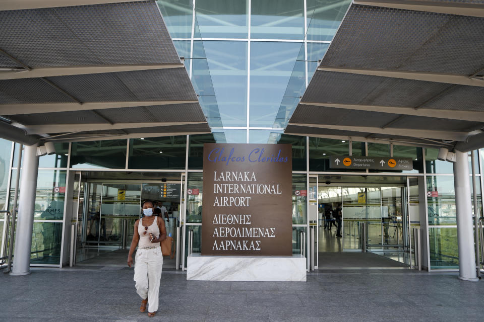 A woman wearing mask walks at Cyprus' main airport at Larnaca on Tuesday, June 9, 2020. Cyprus re-opened its airports on Tuesday to a limited number of countries after nearly three months of commercial air traffic as a result of a strict lockdown aimed at staving off the spread of COVID-19. (AP Photo/Petros Karadjias)