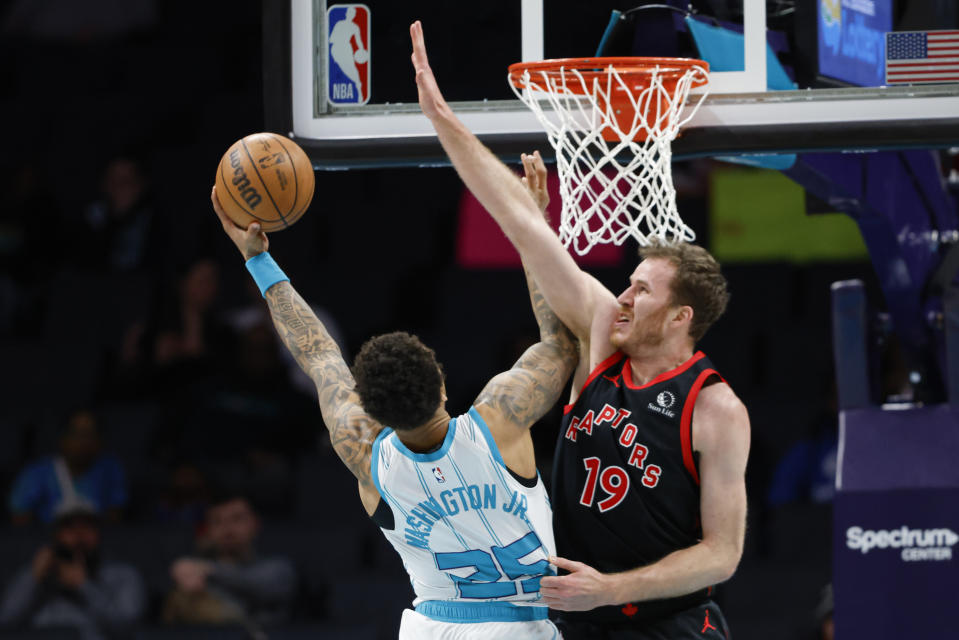 Charlotte Hornets forward P.J. Washington, left, drives to the basket against Toronto Raptors center Jakob Poeltl during the first half of an NBA basketball game in Charlotte, N.C., Wednesday, Feb. 7, 2024. (AP Photo/Nell Redmond)