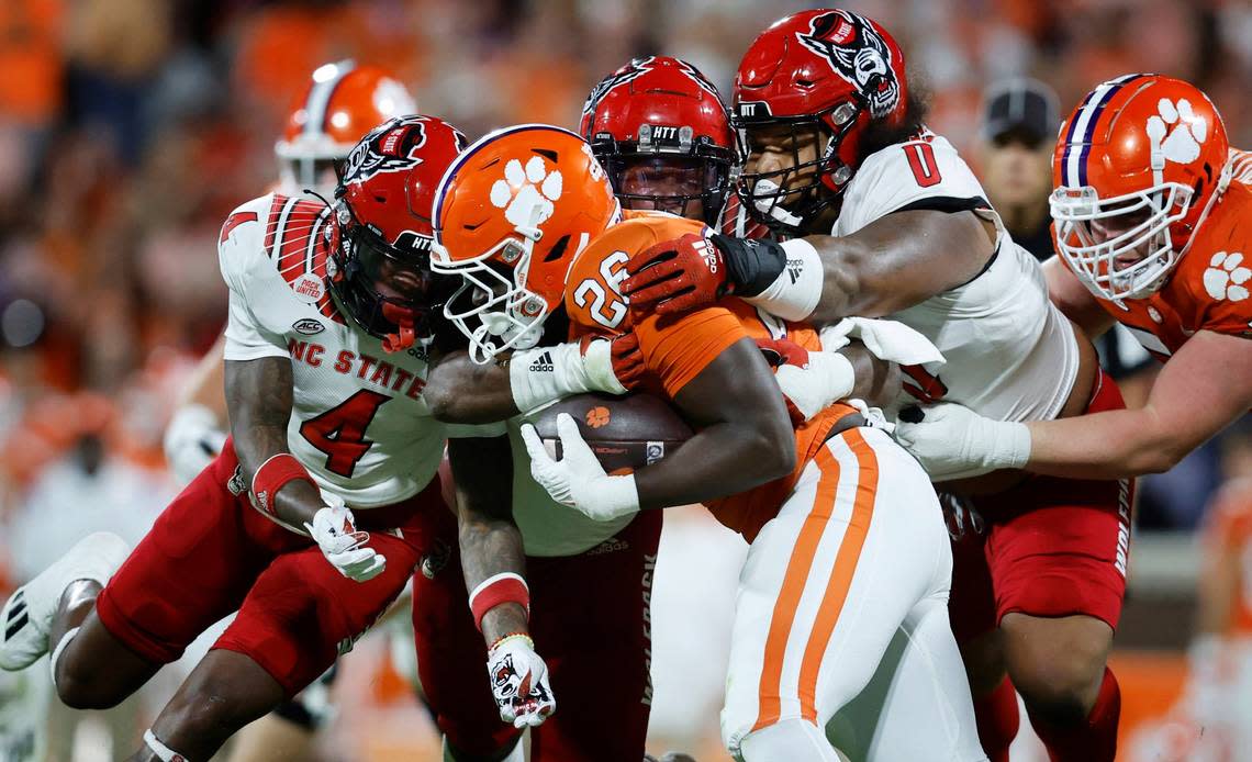 N.C. State linebacker Isaiah Moore (1), safety Cyrus Fagan (4) and defensive tackle Joshua Harris (0) stop Clemson running back Phil Mafah (26) during the first half of N.C. State’s game against Clemson at Memorial Stadium in Clemson, S.C., Saturday, Oct. 1, 2022.