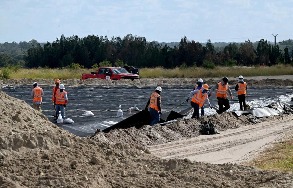 Trabajadores tiran de un revestimiento sobre la tierra de Old Gypsum-Stack North, donde en el futuro se instalarán grandes geotubos para drenar el agua de los sólidos dragados de New Gypsum-Stack South. Operadores de Piney Point anunciaron recientemente un hito con el cierre del compartimento Old Gypsum Stack-South, uno de los cuatro estanques que deben cerrarse en la antigua planta de procesamiento de fosfatos.