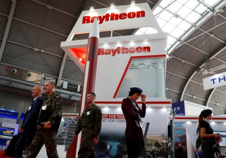 People pass the U.S. defense company Raytheon stand at an international military fair in Kielce